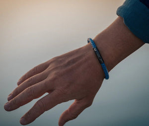 Vertig Leather Bracelet Blue on a man's wrist. Accentuates sophisticated style with its slim blue leather and secure clasp.