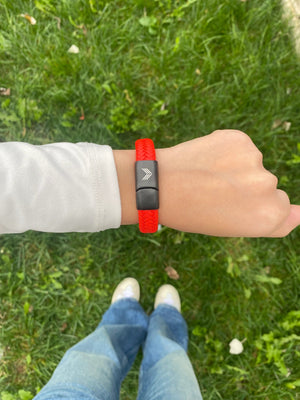 Vertig Magnetic Wide Leather Bracelet Orange on a woman's wrist. A chic accessory, adding a pop of vibrant color.