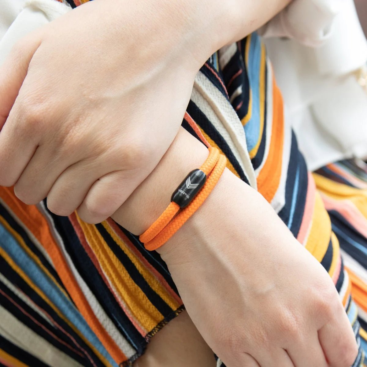 Vertig Magnetic Nautical Paracord Bracelet Orange on a woman&#39;s arm. Comfortable fit, highlighting its unique zest.