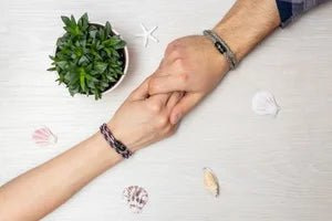 Vertig Magnetic Nautical Paracord Bracelet Red White on a woman&#39;s wrist, hand-in-hand with a man with a paracord bracelet in camo.