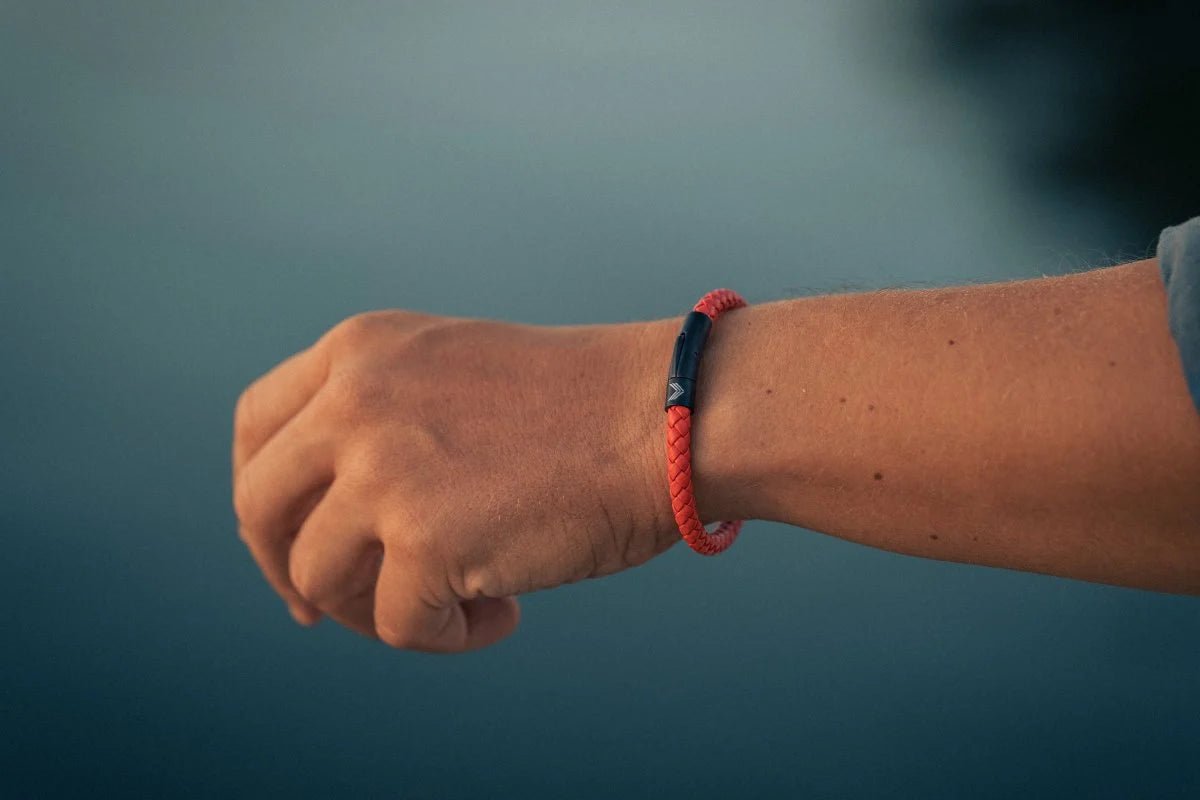 Vertig Leather Bracelet Orange on a man&#39;s wrist. Accentuates dynamic style with its slim orange leather and secure closure.