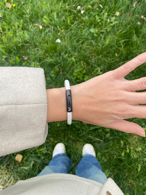 Vertig Leather Bracelet White on a woman's wrist. Adds a sophisticated touch, emphasizing its slender profile and pure white hue.
