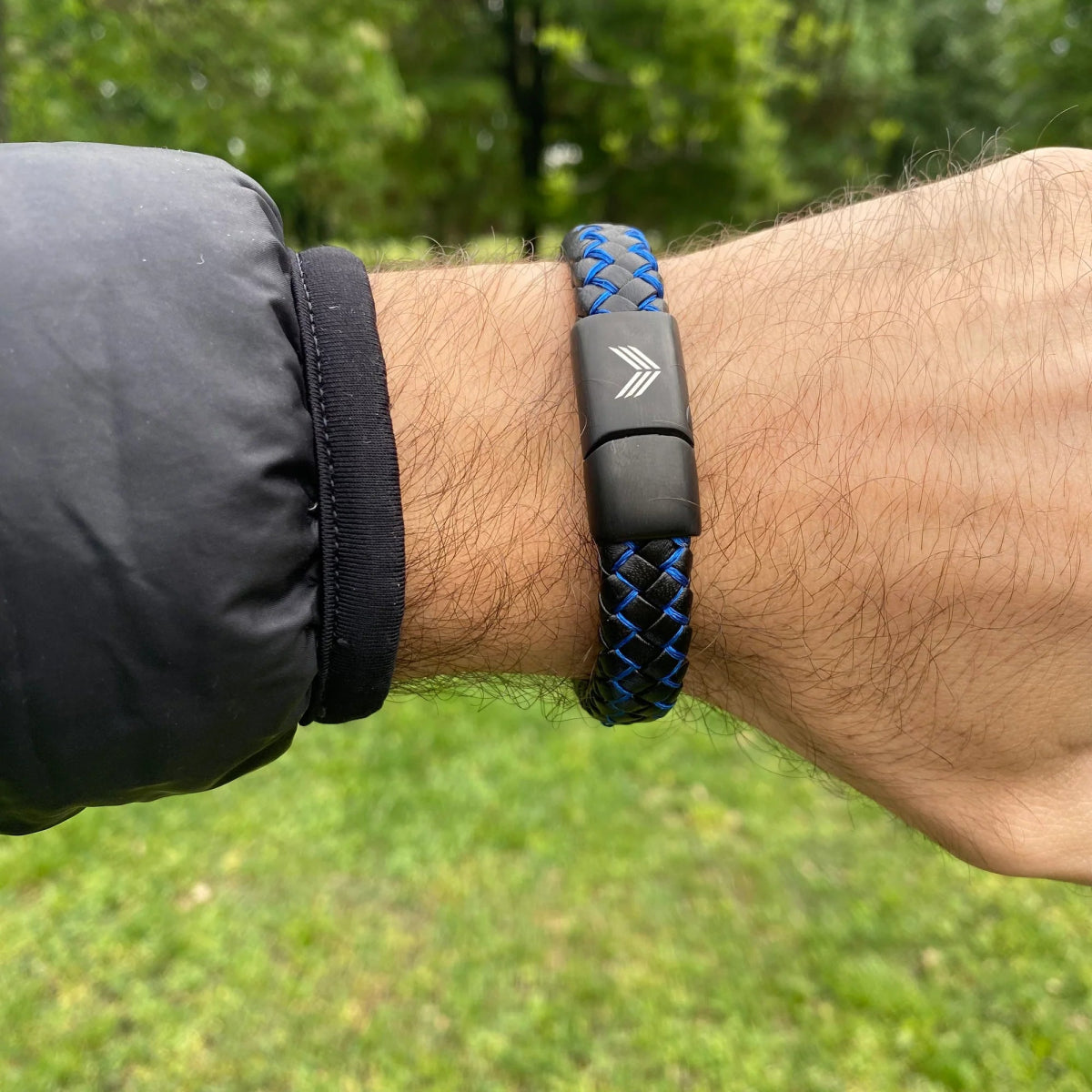 Vertig Magnetic Wide Leather Bracelet Black-Blue on a man&#39;s wrist. Accentuates modern style with its bold black leather and vibrant blue detail.